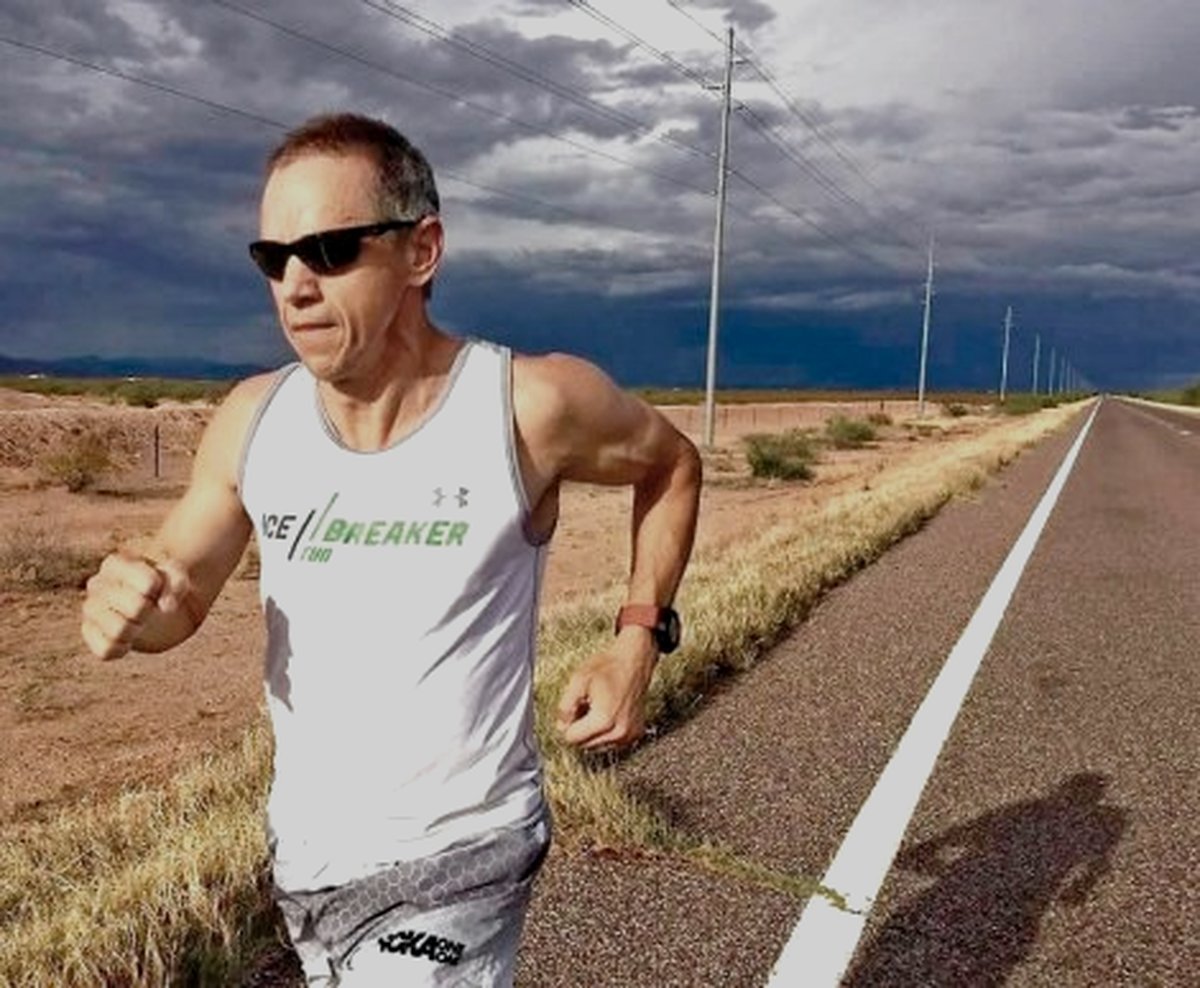 Charlie Engle running through the desert under a storm sky.